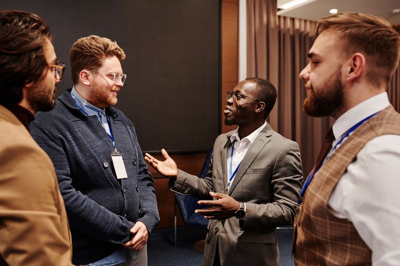Four conference attendees wearing lanyards talk in a small group.